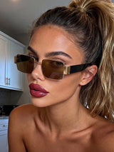 Woman wearing gold-framed sunglasses in a kitchen setting