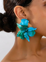 Close-up of a person wearing a blue floral earring against a neutral background