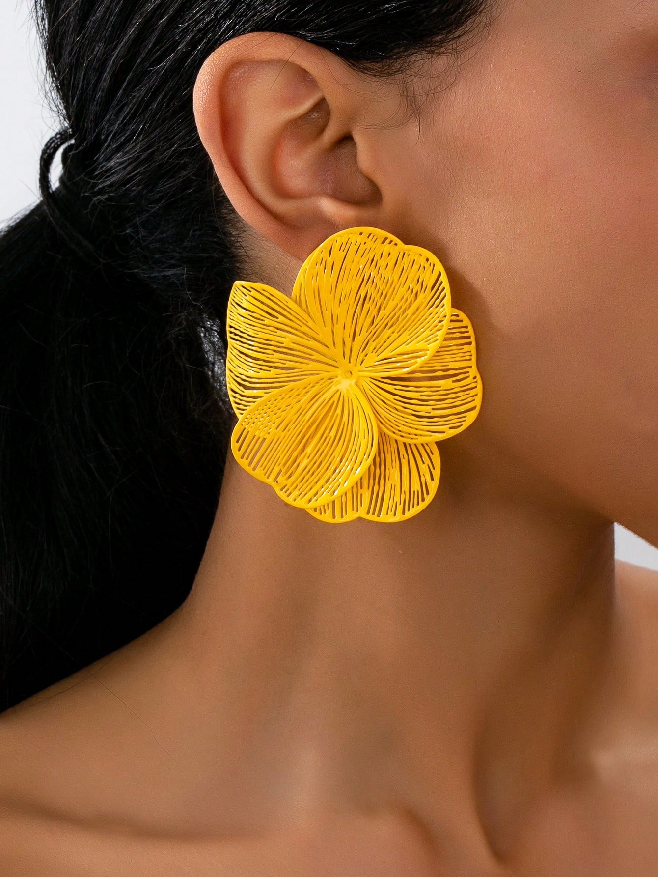 Yellow floral earring worn by a person with a blurred background