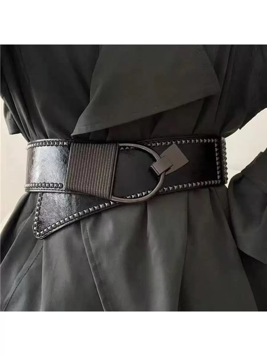 Black belt with decorative buckle worn by a person in a black outfit.