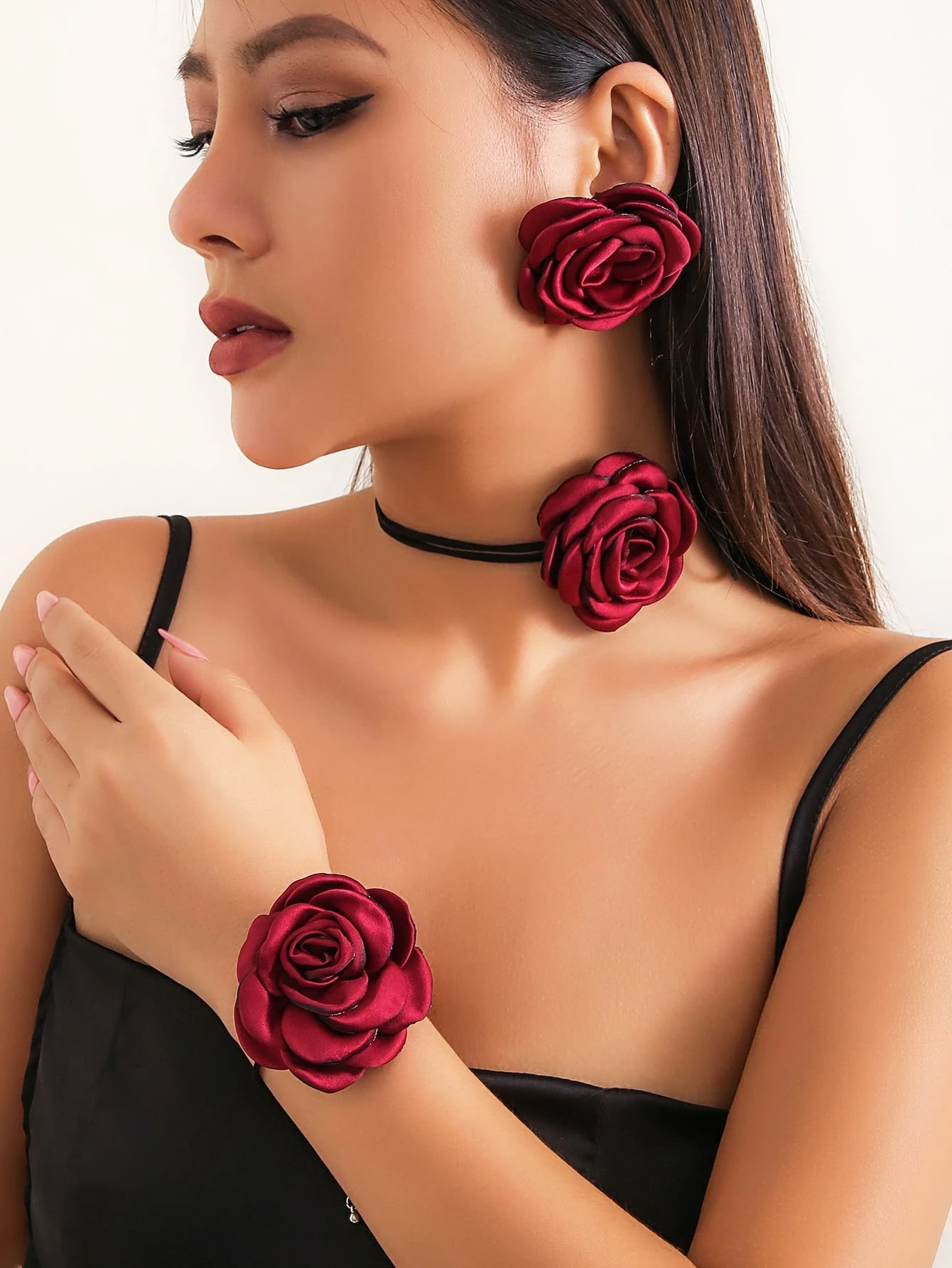 Woman wearing red rose earrings and bracelet on a white background