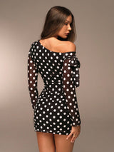 Woman wearing a black polka dot dress against a neutral background