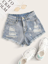 Distressed denim shorts with white sneakers on a light background