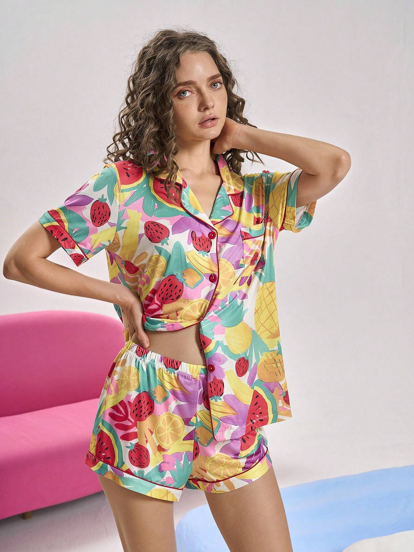 Woman wearing a colorful fruit patterned pajama set against a plain background