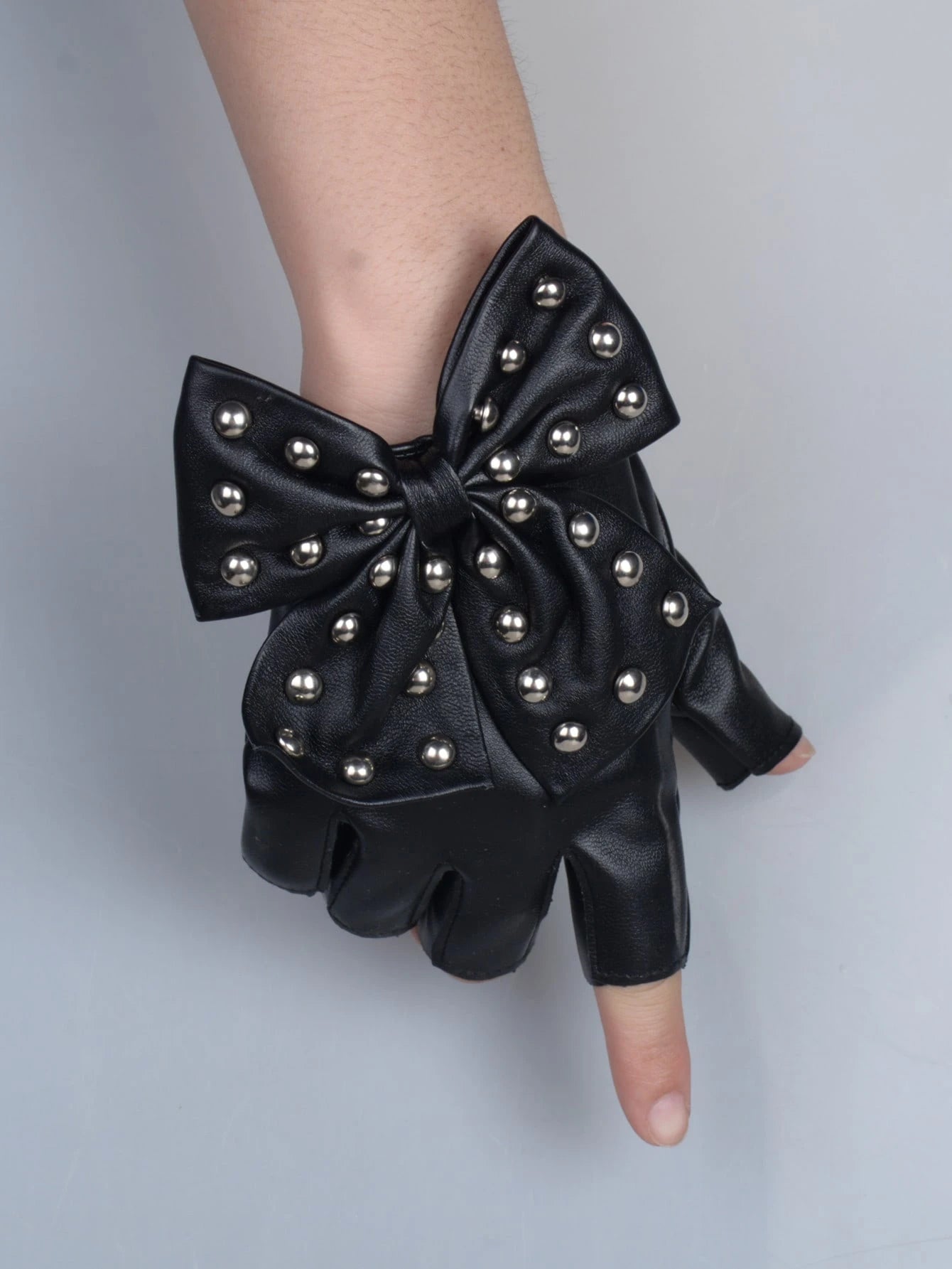 Black leather glove with a large bow and studs on a gray background