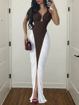 Woman wearing a brown and white dress with a high slit, standing in a room.