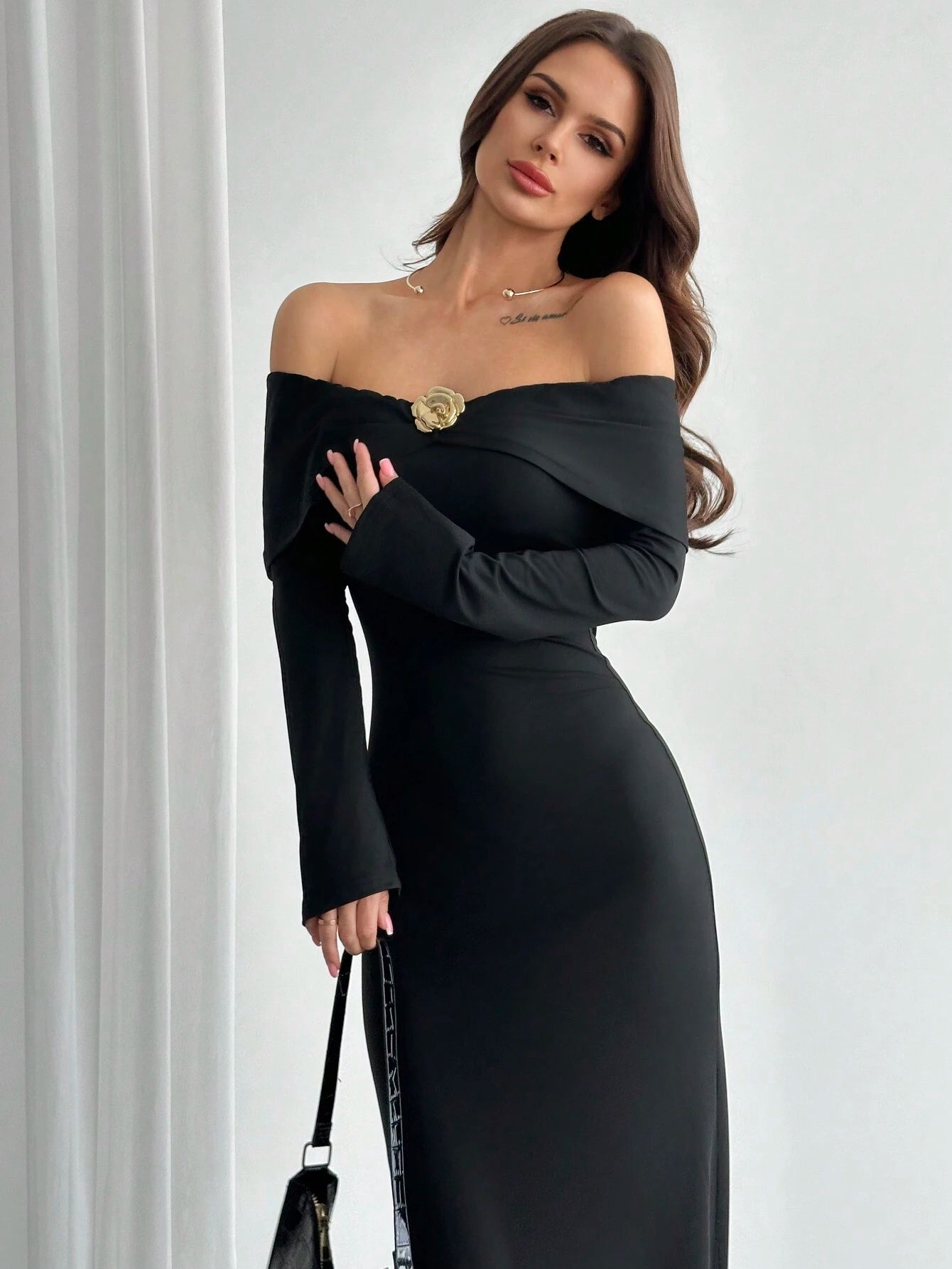 Woman wearing a black off-shoulder dress with a white background