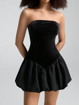 Black strapless dress with a ruffled skirt on a plain background