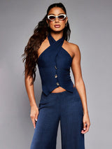 Woman wearing a navy blue halter top and wide-leg pants against a gray background