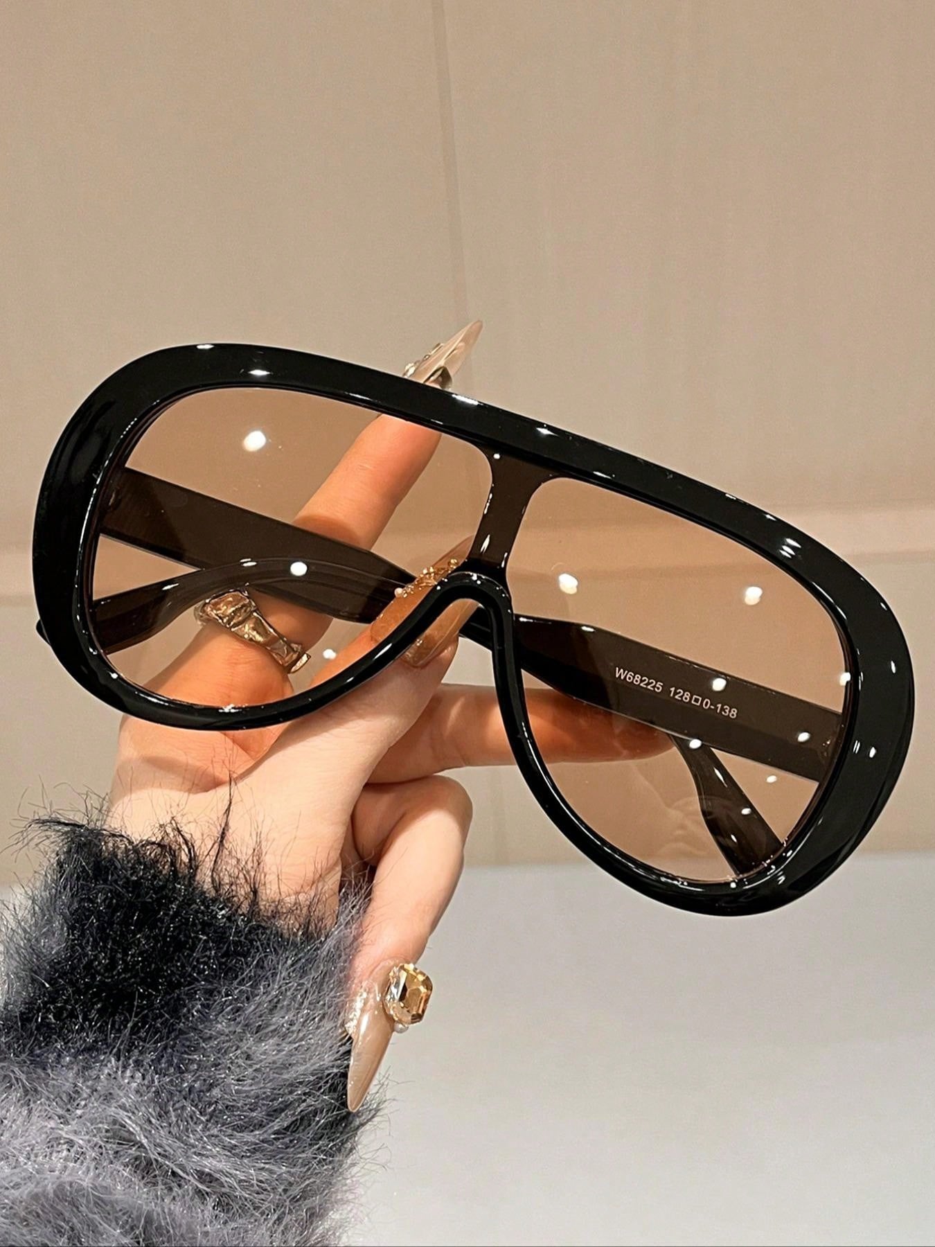 Black sunglasses held by a hand with a blurred background
