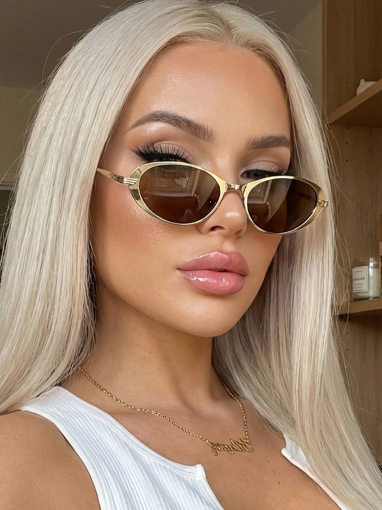 Woman wearing gold sunglasses with a neutral background