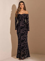 Woman wearing a black floral off-shoulder gown against a beige background