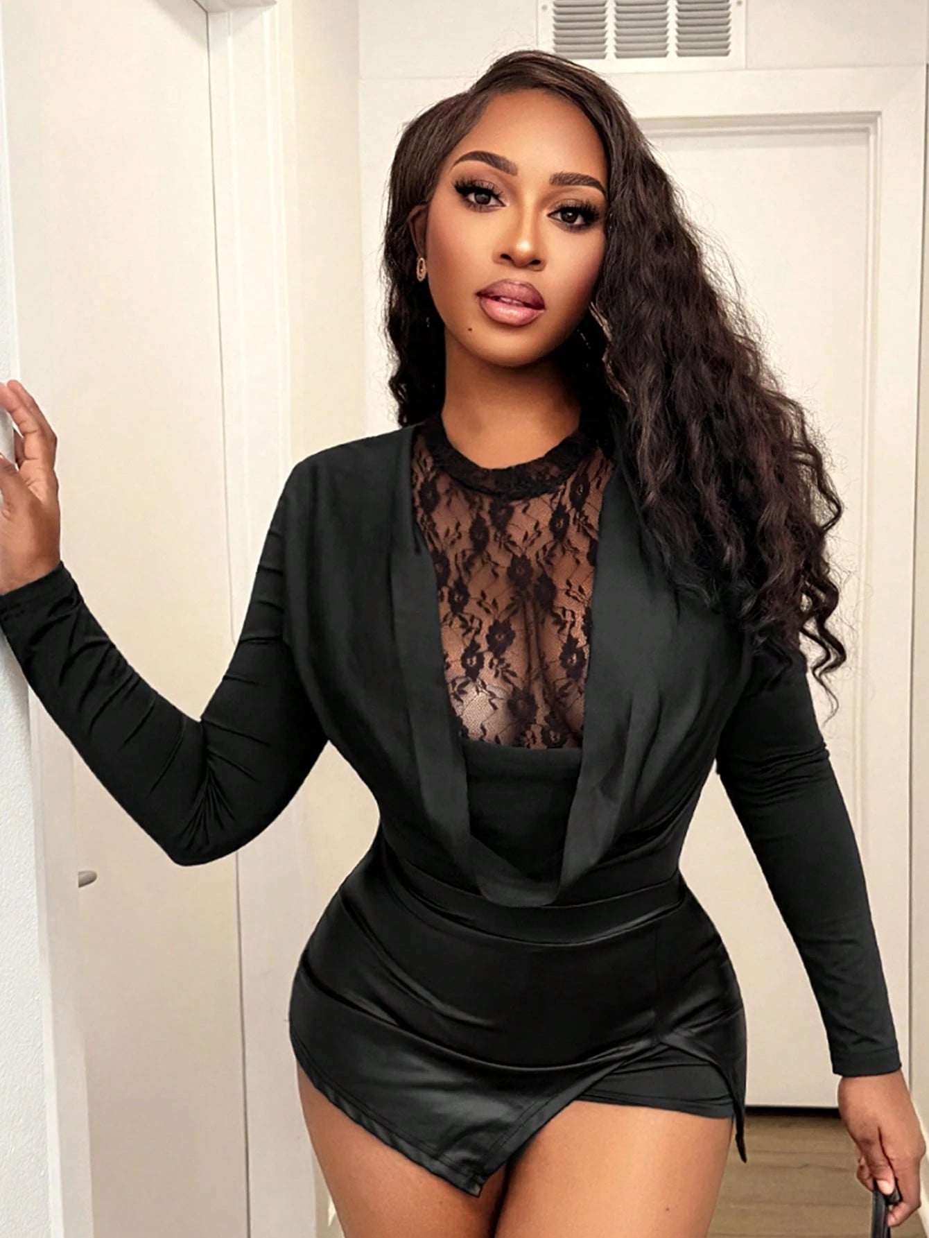 Woman wearing a black outfit with sheer details in a room.