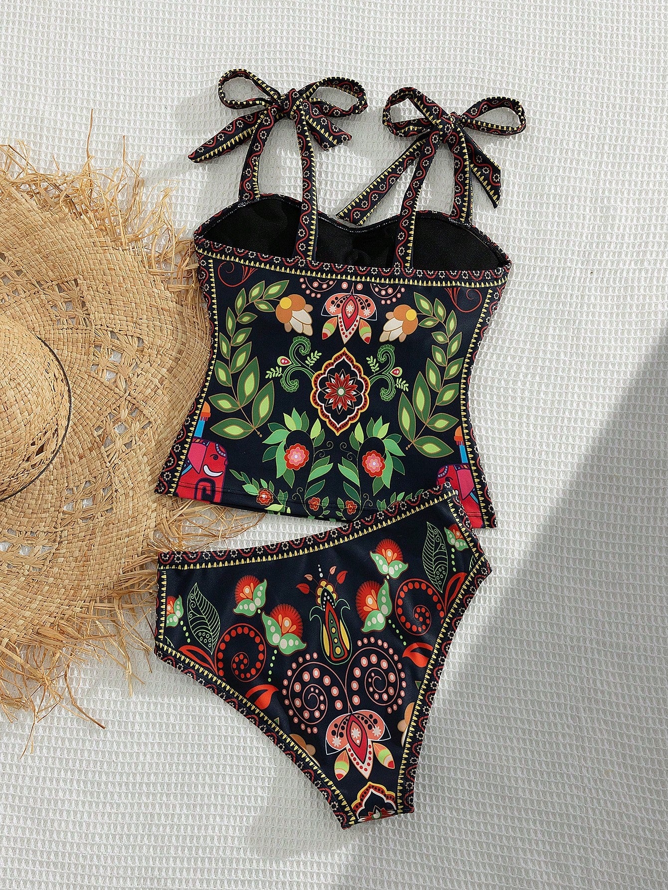 Floral patterned swimsuit with decorative bows on a light background