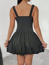 Black dress with thin straps on a plain background