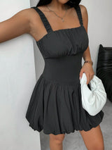 Woman wearing a black dress holding a white clutch against a neutral background