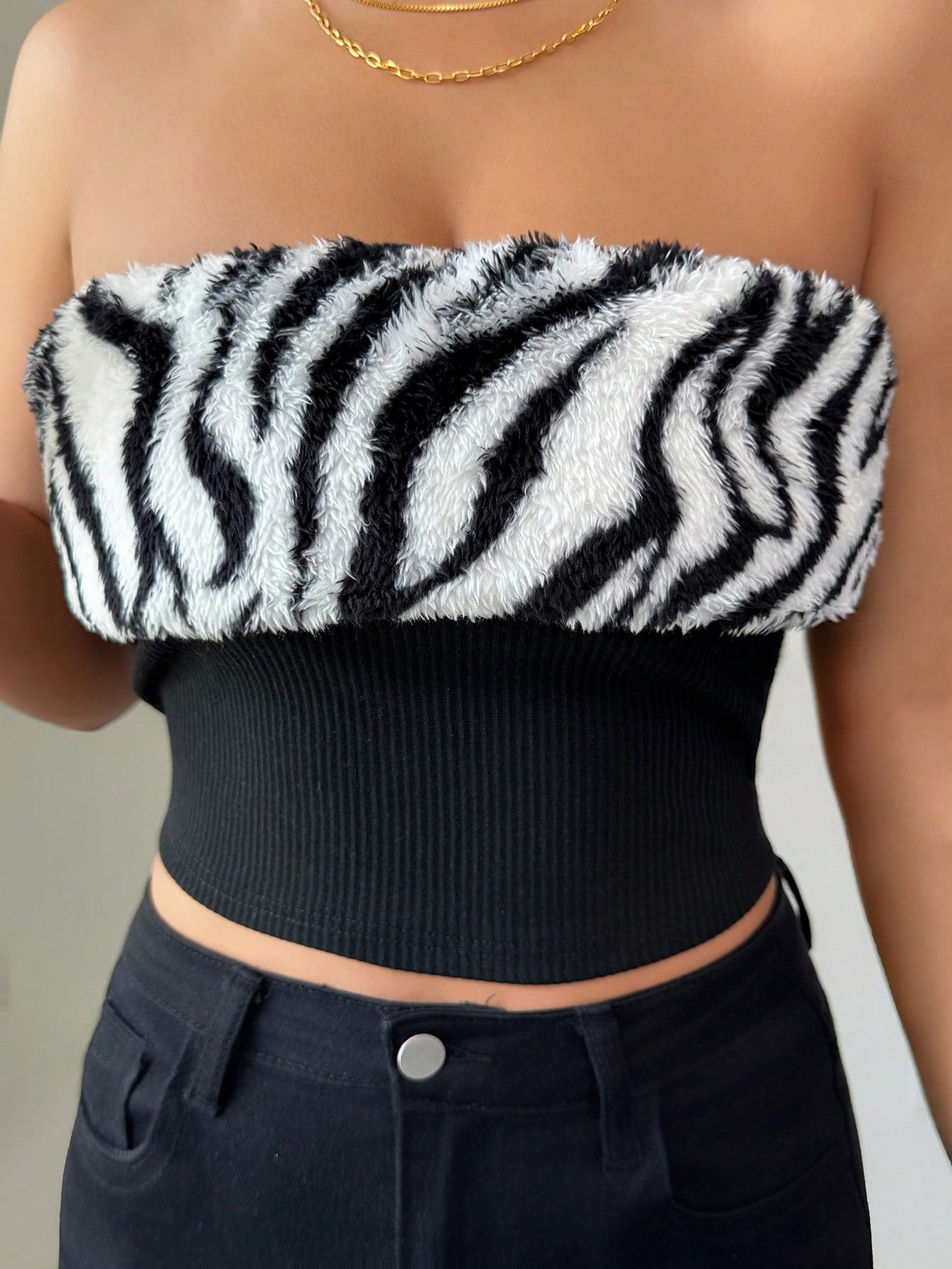 Person wearing a zebra print top and black pants against a neutral background