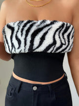 Person wearing a zebra print top and black pants against a neutral background