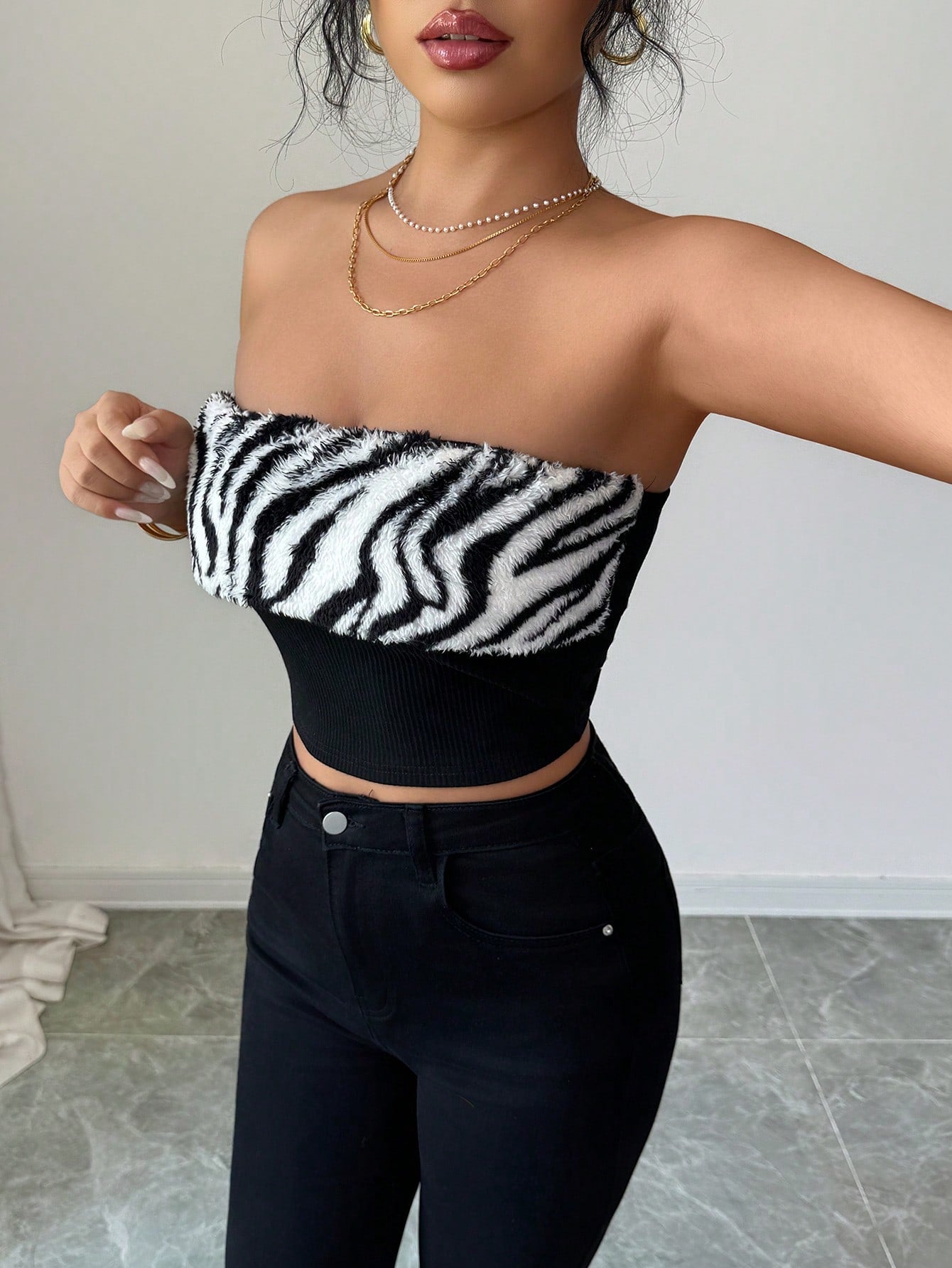 Person wearing a black and white zebra print tube top with high-waisted black pants.