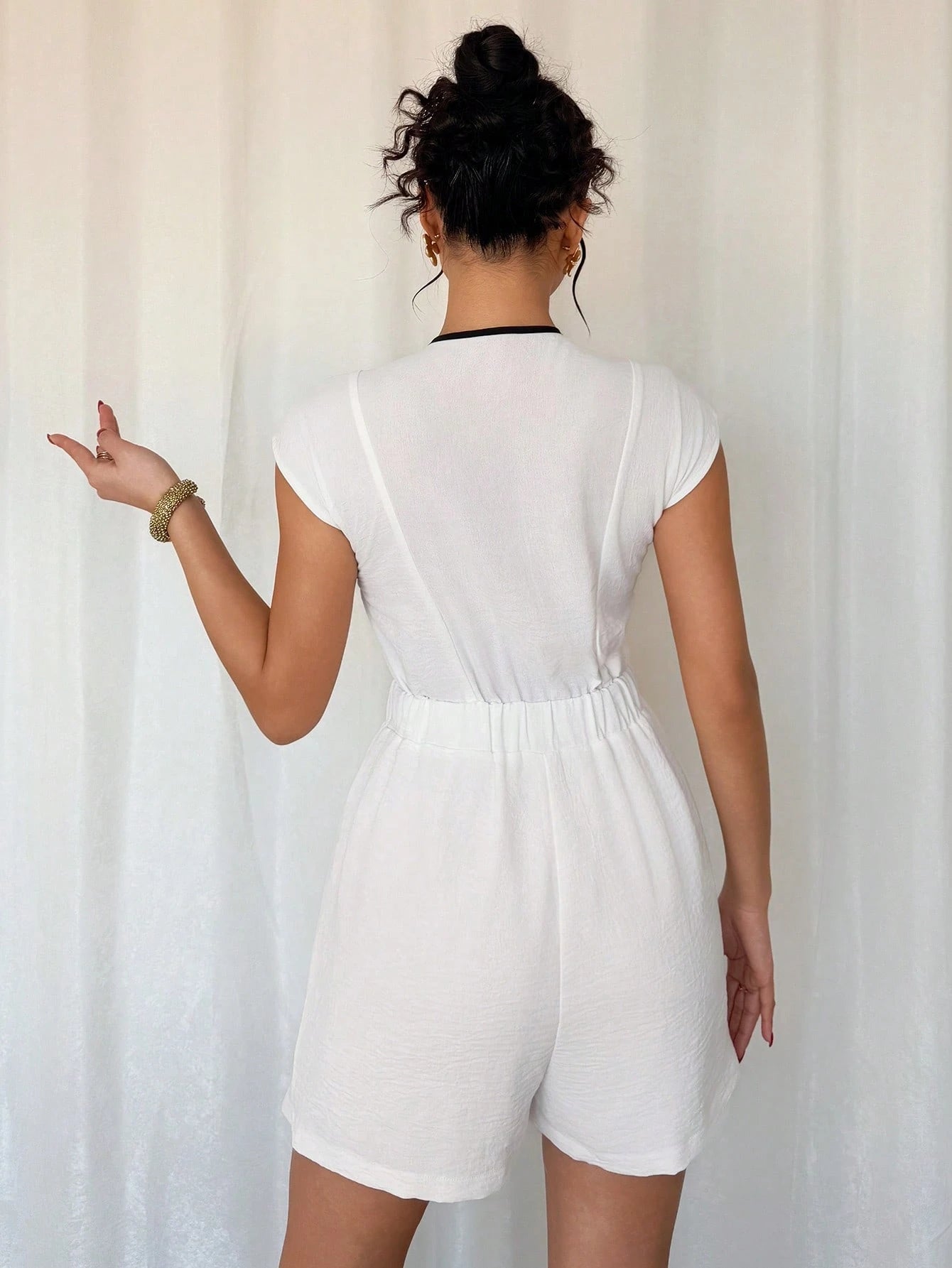 Person wearing a white romper against a plain background
