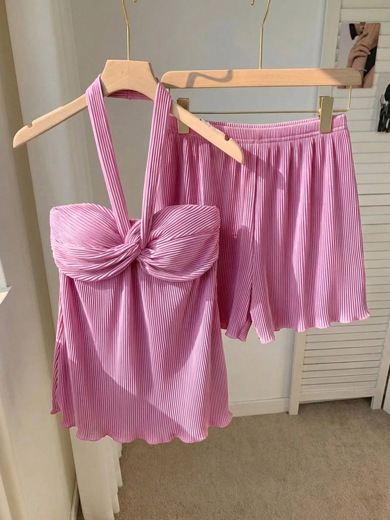 Pink striped top and skirt set on hangers against a neutral background