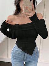 A woman takes a mirror selfie wearing a black off-the-shoulder ribbed knit top with long sleeves and light blue jeans.