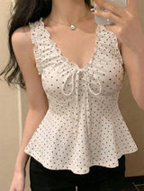 White polka dot top worn by a person against a neutral background