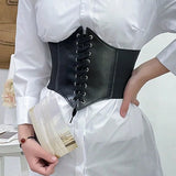 Person wearing a black leather corset belt over a white shirt.