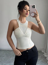 Woman taking a mirror selfie wearing a white top and black pants.