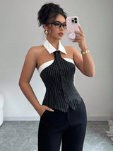 Woman taking a mirror selfie wearing a black and white pinstripe top and black pants.