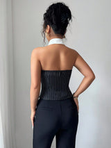 Woman wearing a black pinstripe corset and high-waisted pants against a plain background