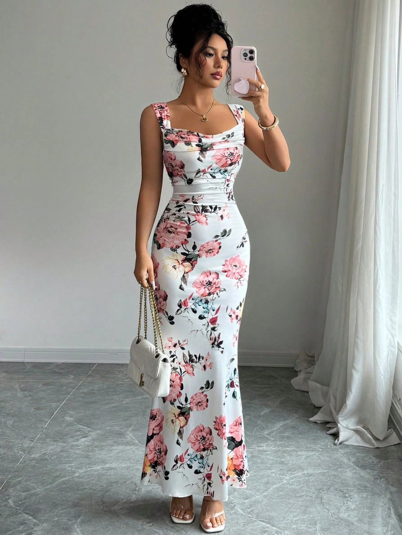 Woman taking a mirror selfie wearing a floral dress in a room with a white curtain.