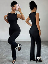 Woman wearing a black jumpsuit taking a mirror selfie.