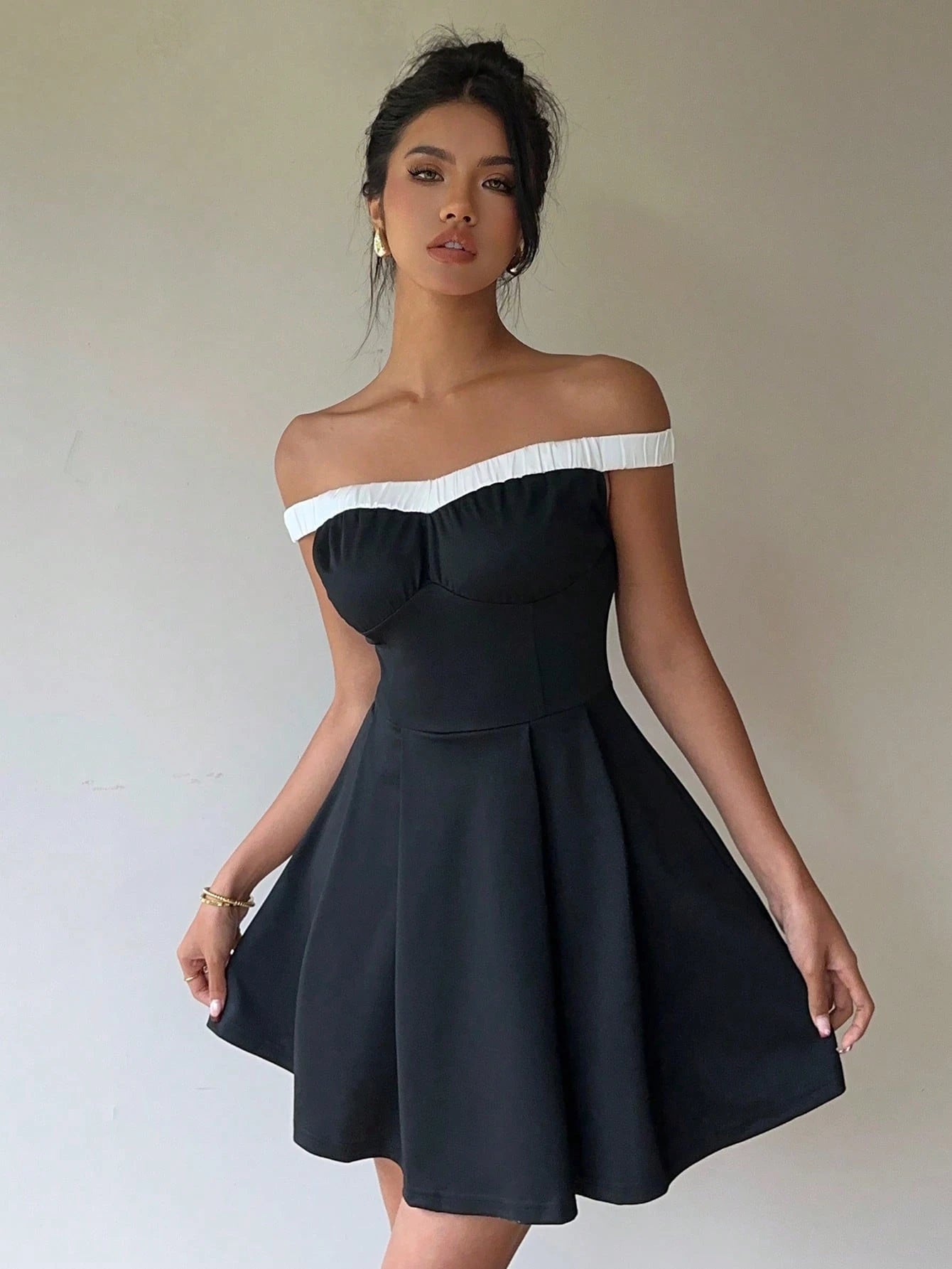 Woman wearing a black and white off-shoulder dress against a plain background