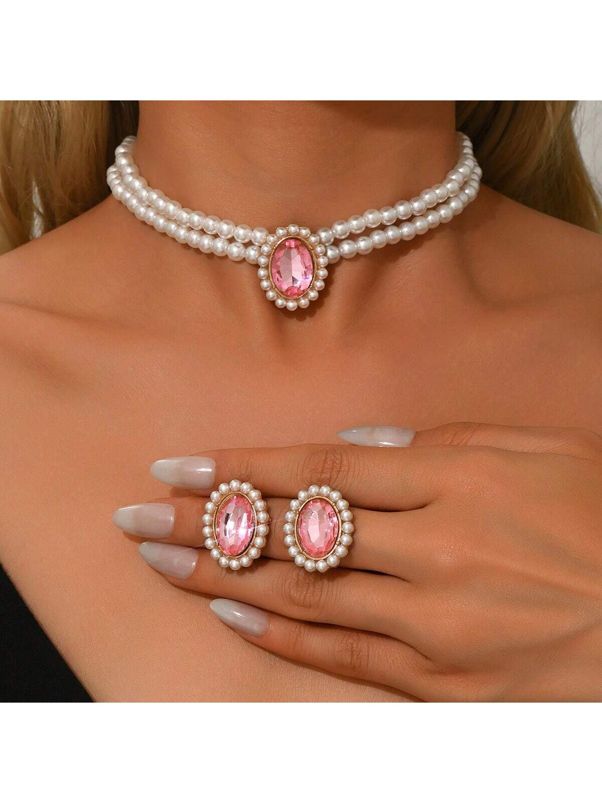 Jewelry set with pink gemstones including a necklace, earrings, and ring on a model.