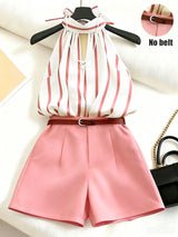 Striped top and pink shorts with a belt on a hanger, black handbag in the background.