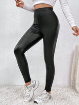 Person wearing black shiny leggings with a white background