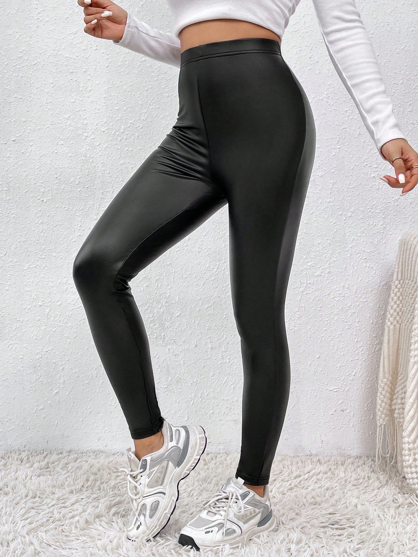 Person wearing black shiny leggings with a white background