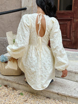 Person wearing a white lace dress sitting on steps outdoors.