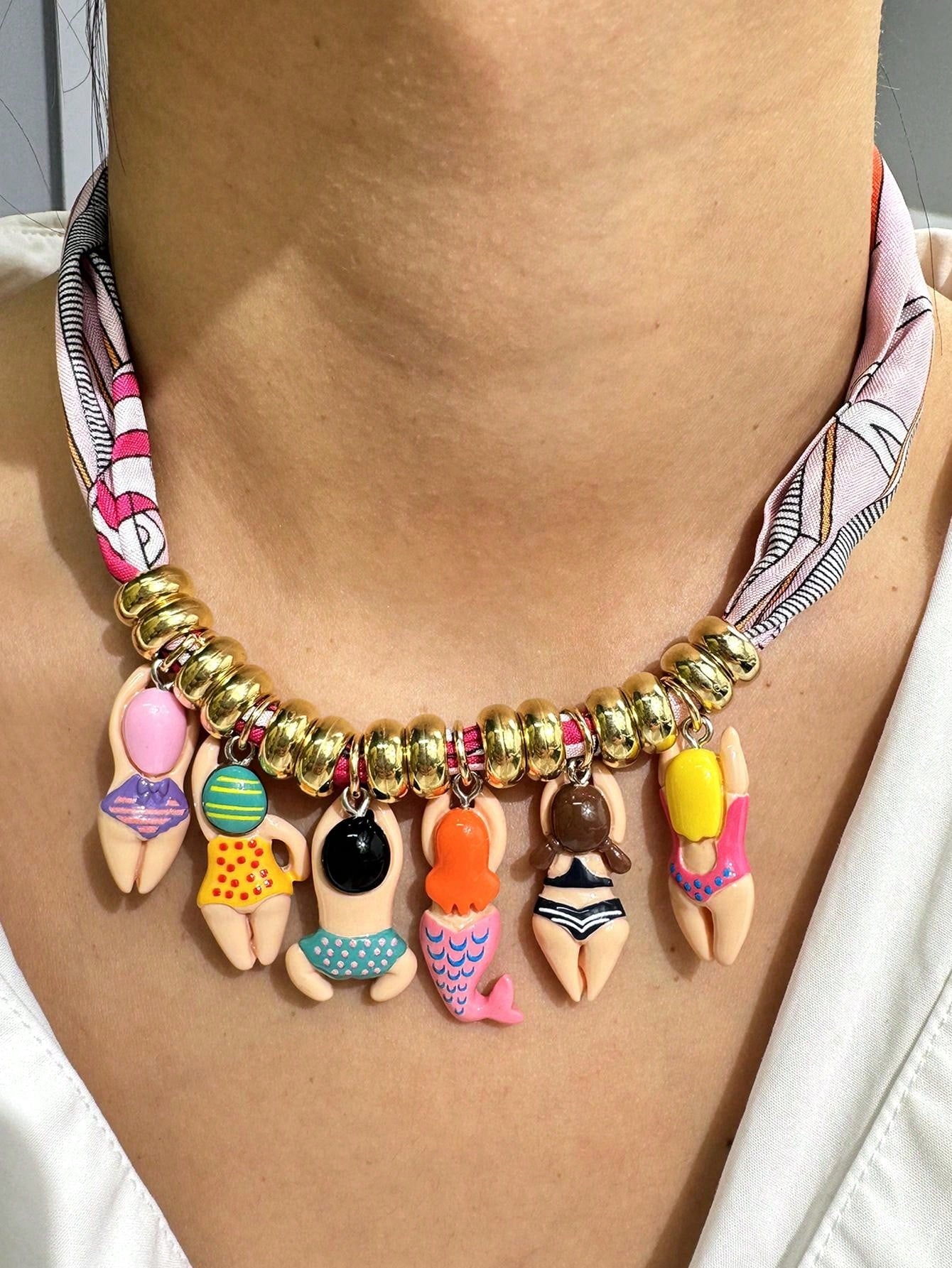 Necklace with colorful charms on a person wearing a patterned shirt.