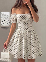 A woman wearing an off-the-shoulder white dress with black polka dots, holding a white quilted handbag. The image includes a detail inset showing the fabric texture and text reading 'DECORATIVE DETAILS'.