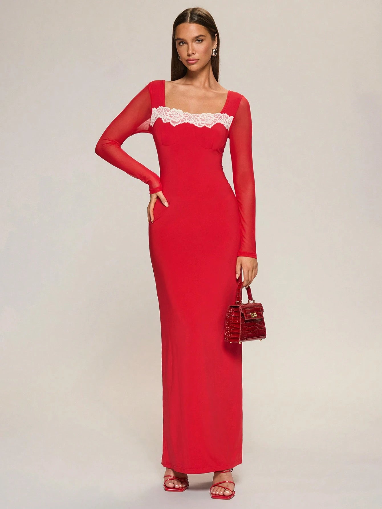 Woman wearing a red dress with lace detailing on a plain background
