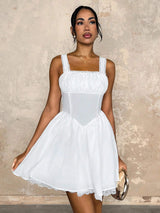 Woman wearing a white dress against a textured beige wall