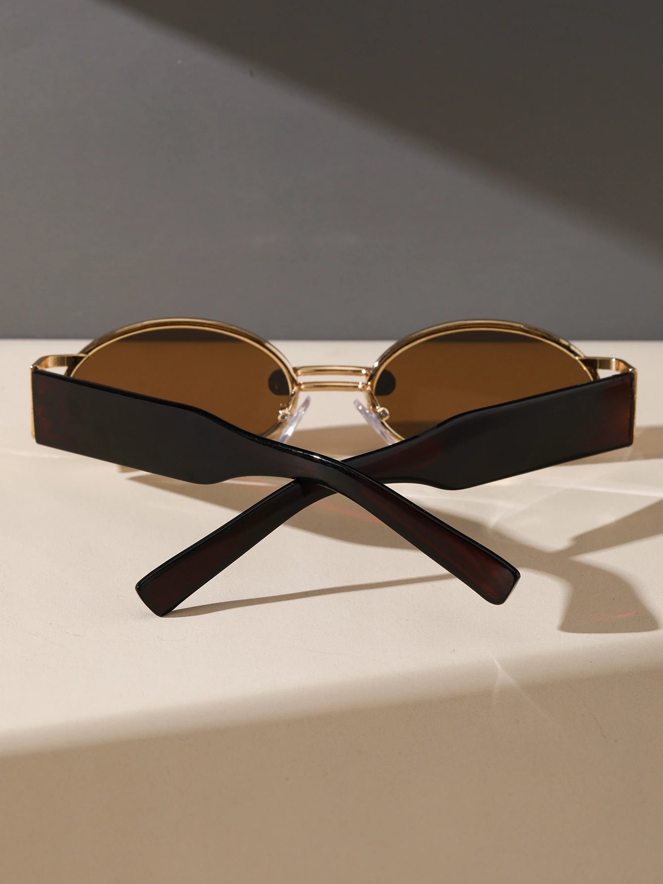 Sunglasses with black frame and brown lenses on a light surface with a dark background