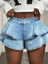 Person wearing a white mesh top and blue denim shorts with ruffled layers.