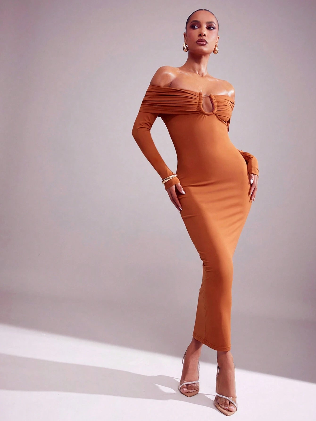 Woman wearing a brown off-shoulder dress against a plain background