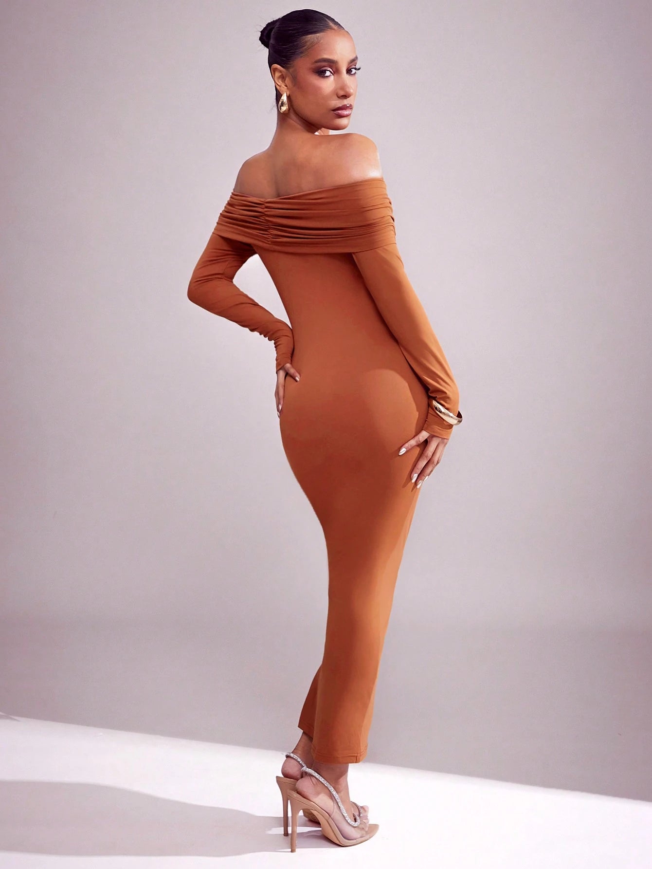 Woman wearing a brown off-shoulder dress against a plain background