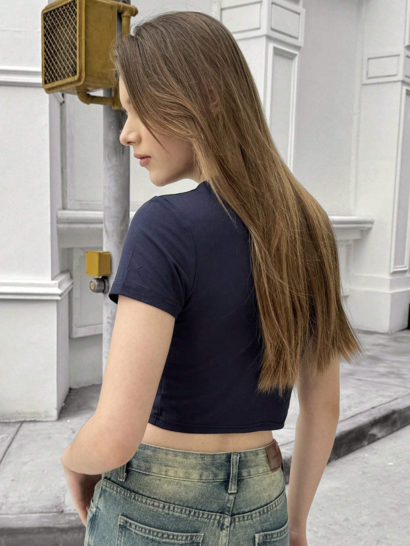 Person wearing a black crop top and denim shorts in an urban setting