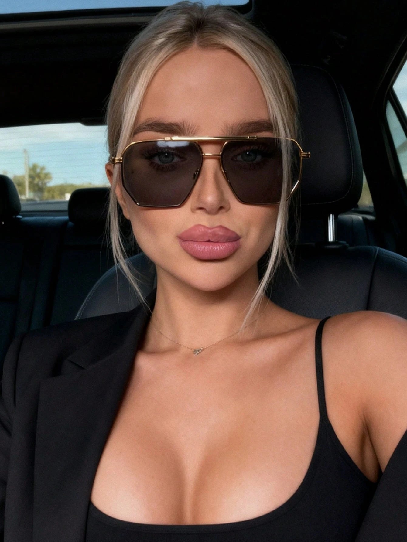Woman wearing sunglasses and a black outfit inside a car