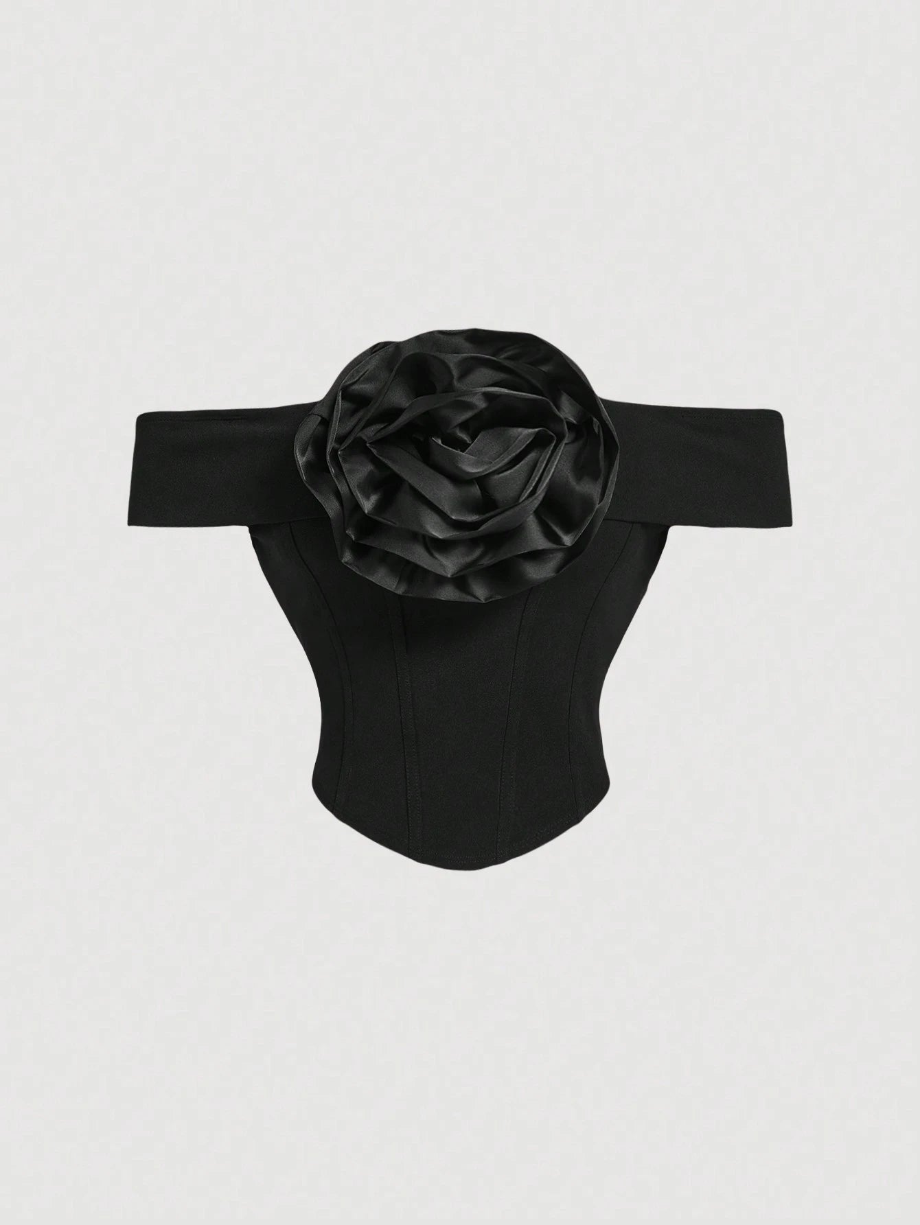 Black off-shoulder top with a large flower detail on a light gray background